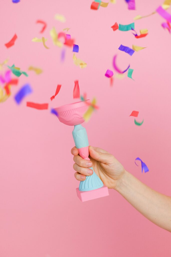 Confetti and trophy on pink background
