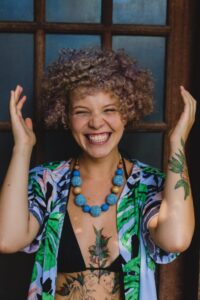Woman with curly hair throwing her hands in the air with excitement